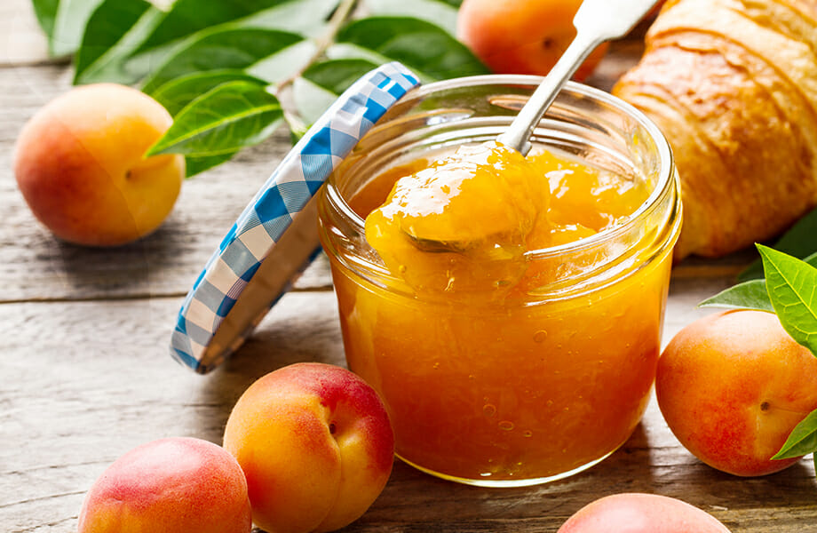 Flascó de vidre amb melmelada d'albercoc i fruits de fons per mostrar el potencial de la comercialització de conserves gourmet