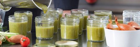 Produttore che versa la crema in barattoli in vetro dove è necessario spazio vuoto per la sterilizzazione.